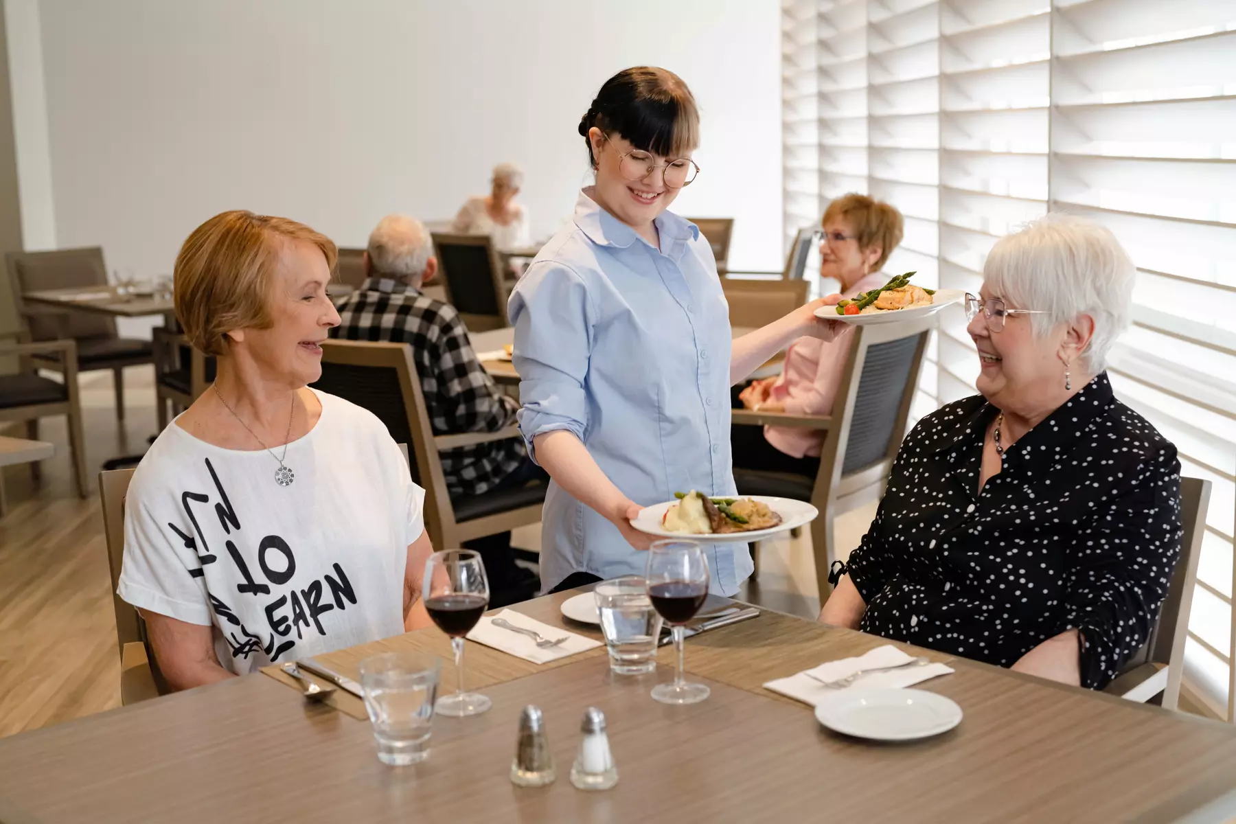 Chartwell server serving food to senior resident / Un serveur de Chartwell sert de la nourriture à une personne âgée