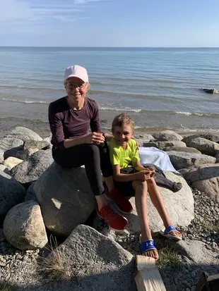Colleen and her grand son resting and posing while sitting on a rock near beach