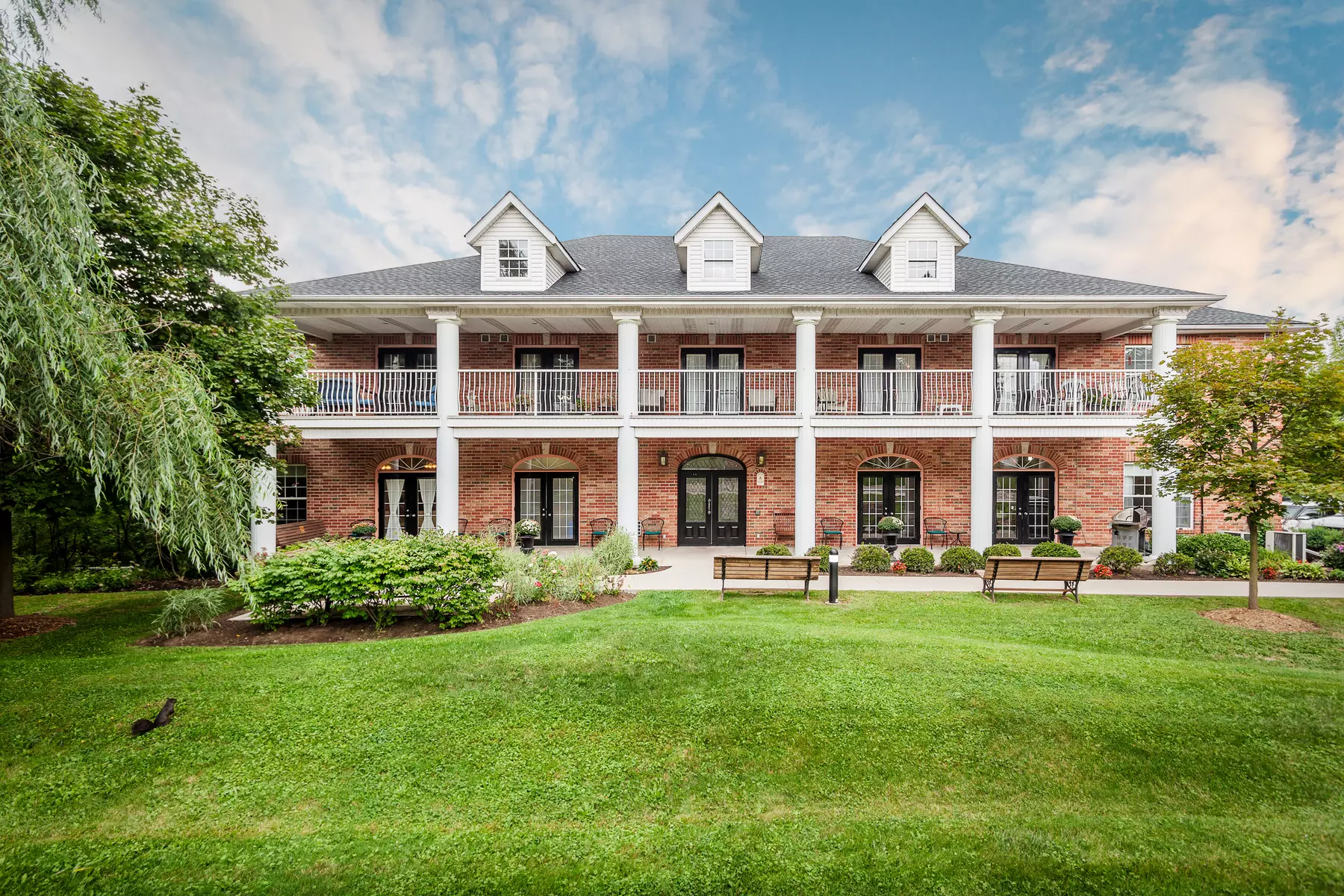 Gorgeous front of building with gardens and patio at Chartwell Georgian Retirement Residence.